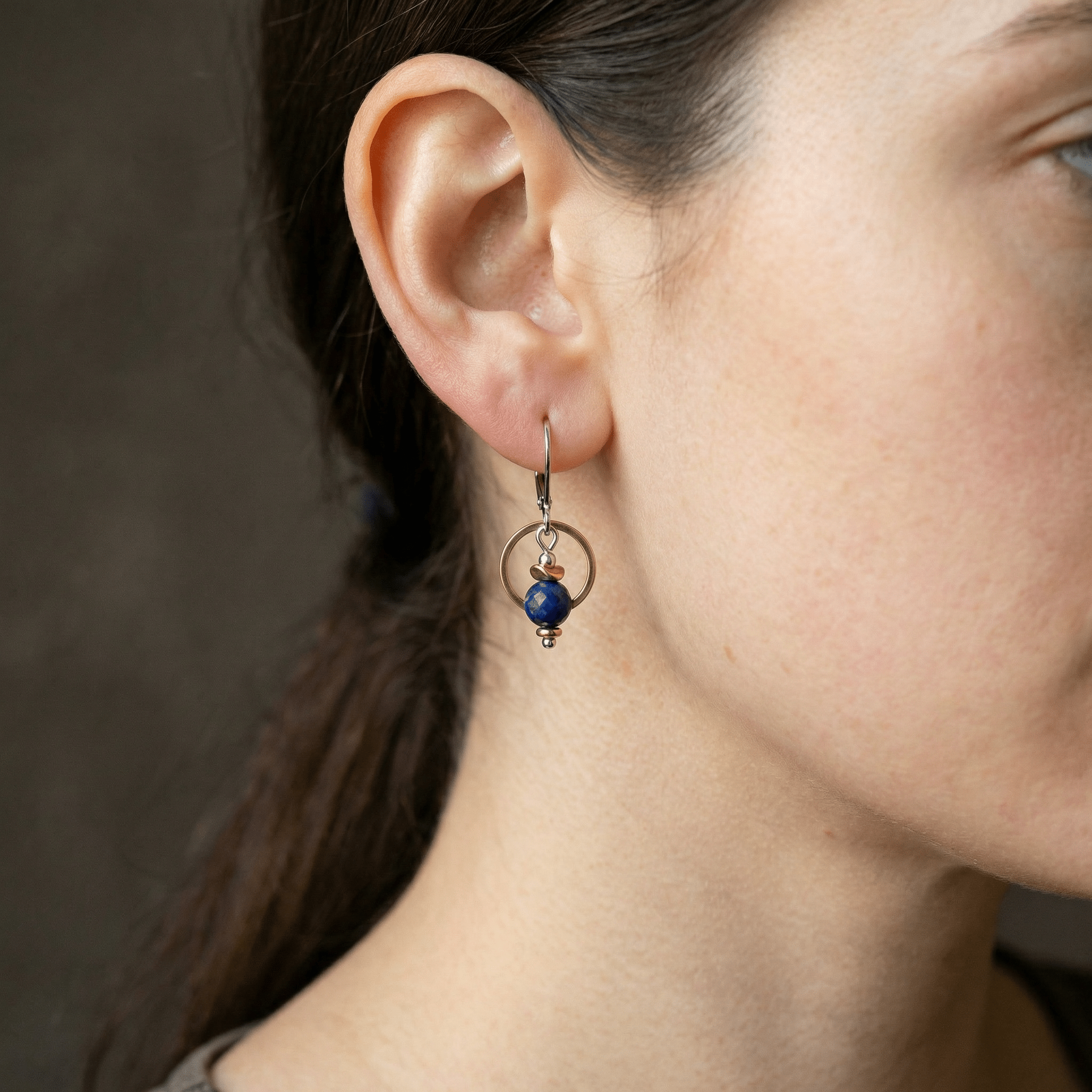 Femme portant des boucles d'oreilles pendantes avec agate bleue avec cercle doré, bijou artisanal fait main au Québec